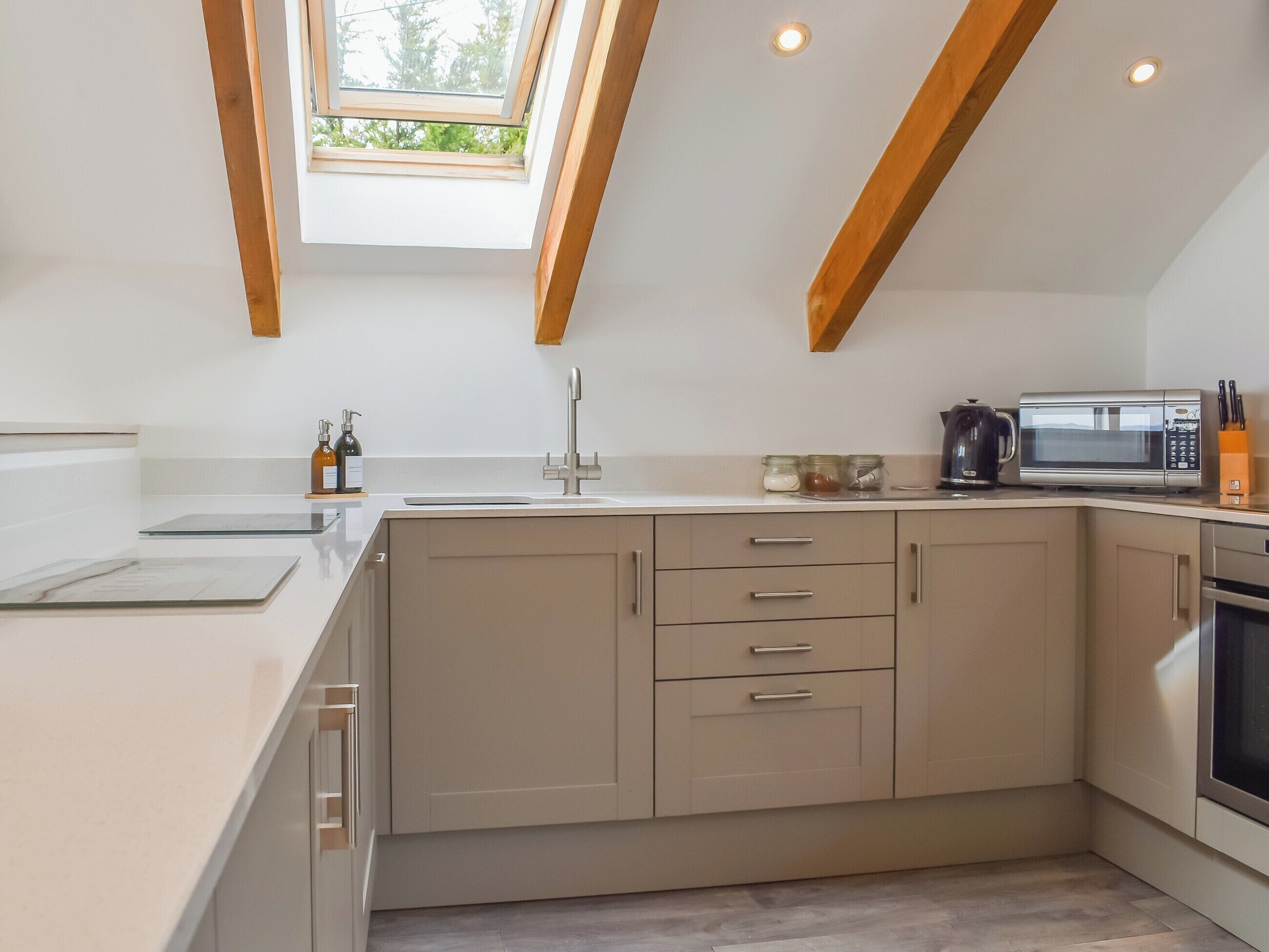 A modern kitchen with a skylight, a built-in microwave, and a coffee maker.