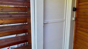 A wooden door with a white frame, a grey tiled entrance, and a wooden bench outside. - New 2 bedroom house, Sainte-Anne (Sainte-Anne)