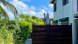 A modern two-story house with a concrete driveway leading to a wooden gate. - New 2 bedroom house, Sainte-Anne (Sainte-Anne)
