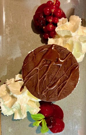 A dessert plate with a chocolate cake, whipped cream, red berries, and mint leaves. - Whirlpool Suite Amadeus for an Unforgettable Holiday (Bad Waltersdorf)