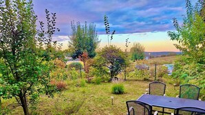 An outdoor seating area with a table and chairs, surrounded by various plants and trees. - Whirlpool Suite Amadeus for an Unforgettable Holiday (Bad Waltersdorf)