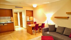 A modern living room with a sofa, a red ottoman, and a dining area with a table and chairs. - Whirlpool Suite Amadeus for an Unforgettable Holiday (Bad Waltersdorf)