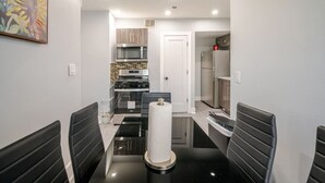 A modern kitchen with a microwave, stove, and refrigerator. There is a black countertop and a chair in the foreground. - 2 Bed Apt in BlackRock by beach (Bridgeport)