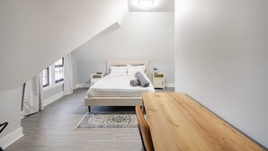 A bedroom with a large bed, a wooden bench, a nightstand, and a small table. - 2 Bed Apt in BlackRock by beach (Bridgeport)