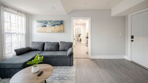 A modern living room with a grey sofa, a coffee table with a plant, and a painting on the wall. - 2 Bed Apt in BlackRock by beach (Bridgeport)