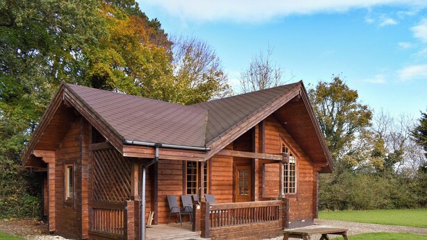 A wooden cabin with a porch, a picnic table, and a gravel pathway. - 2 bedroom accommodation in Staintondale near Scarborough (Staintondale near Scarborough)