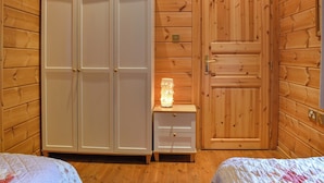 A wooden cabin room with a wardrobe, a bedside table with a lamp, and a bed. - 2 bedroom accommodation in Staintondale near Scarborough (Staintondale near Scarborough)
