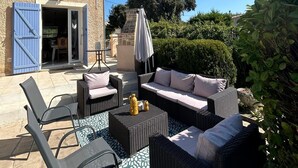 An outdoor patio with wicker furniture, a table, and a chair.