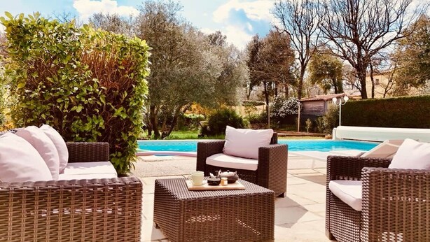 A poolside area with wicker furniture and a view of a swimming pool.