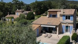 A villa with a pool, surrounded by greenery and hills.