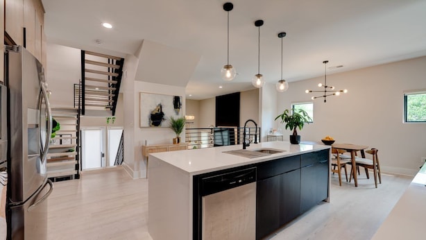 Una cocina moderna con una isla central, lavavajillas integrado e iluminación colgante.