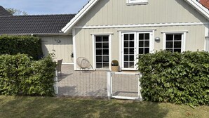 Une maison à deux étages, avec une façade grise, des boiseries blanches et un toit recouvert de tuiles.