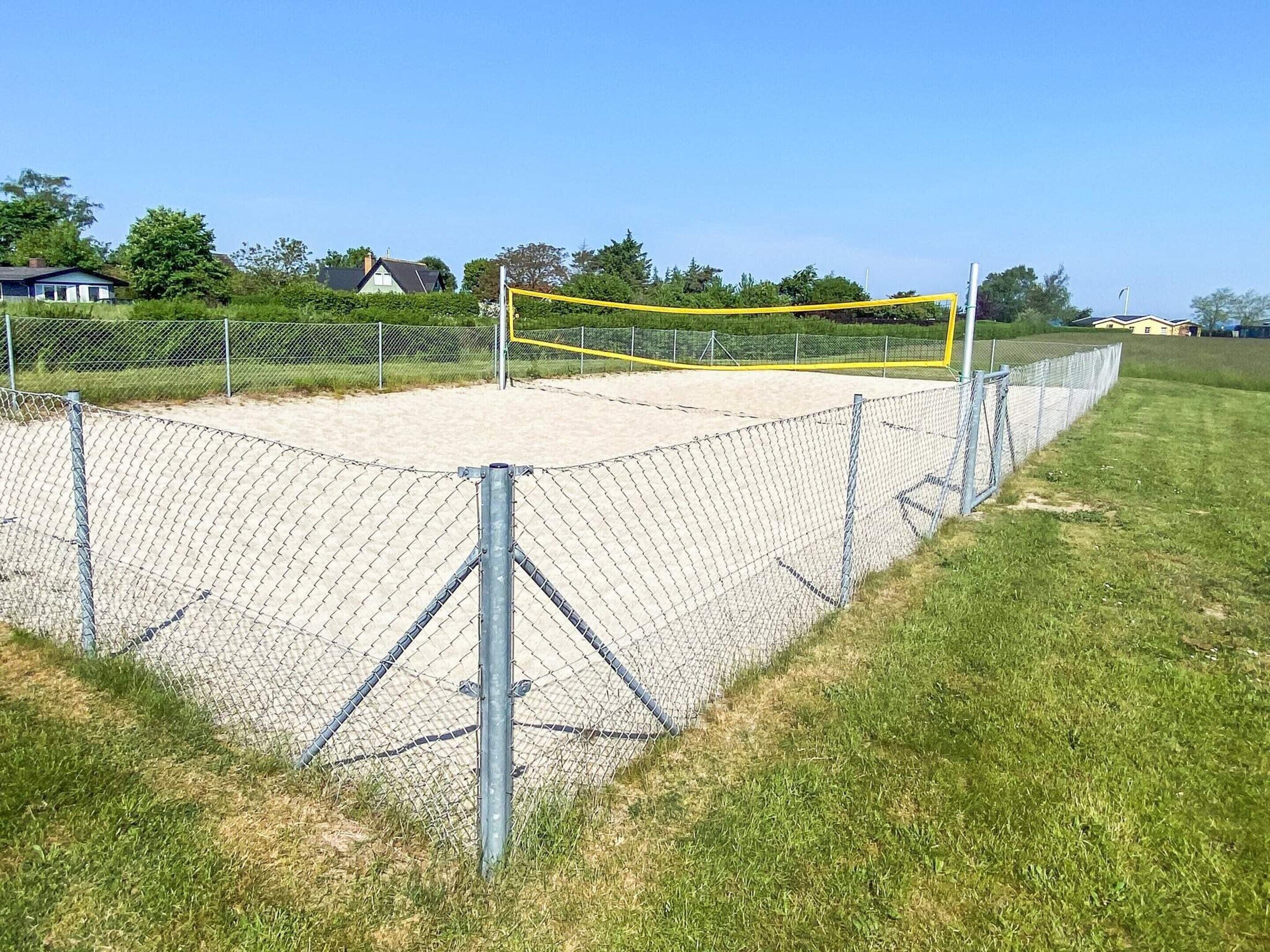 A fenced sports court with a volleyball net.