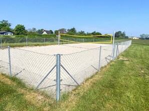 A fenced sports court with a volleyball net.
