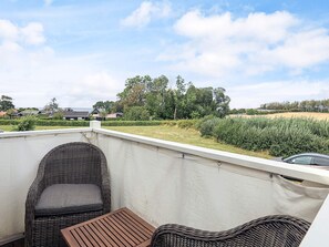 A balcony with wicker furniture, a view of a residential area, and a car parked nearby. - 5 Star Holiday Home in Brenderup Fyn (Middelfart)