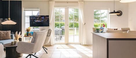 A modern living room with a sofa, armchair, and a flat-screen TV.