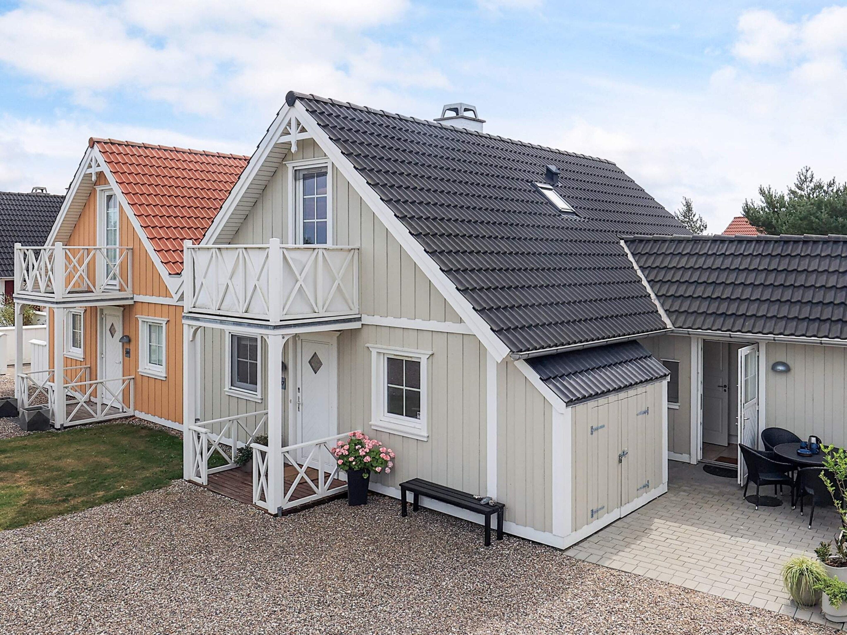 A two-story house with a balcony, a covered porch, and a patio area with a table and chairs.