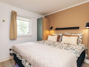 A bedroom with a bed, a window, a door, and a wall-mounted shelf. - 5 Star Holiday Home in Brenderup Fyn (Middelfart)