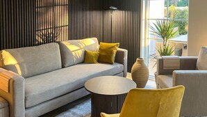 Ein modernes Wohnzimmer mit einem grauen Sofa, gelben Kissen, einem runden Couchtisch und einem gelben Sessel.