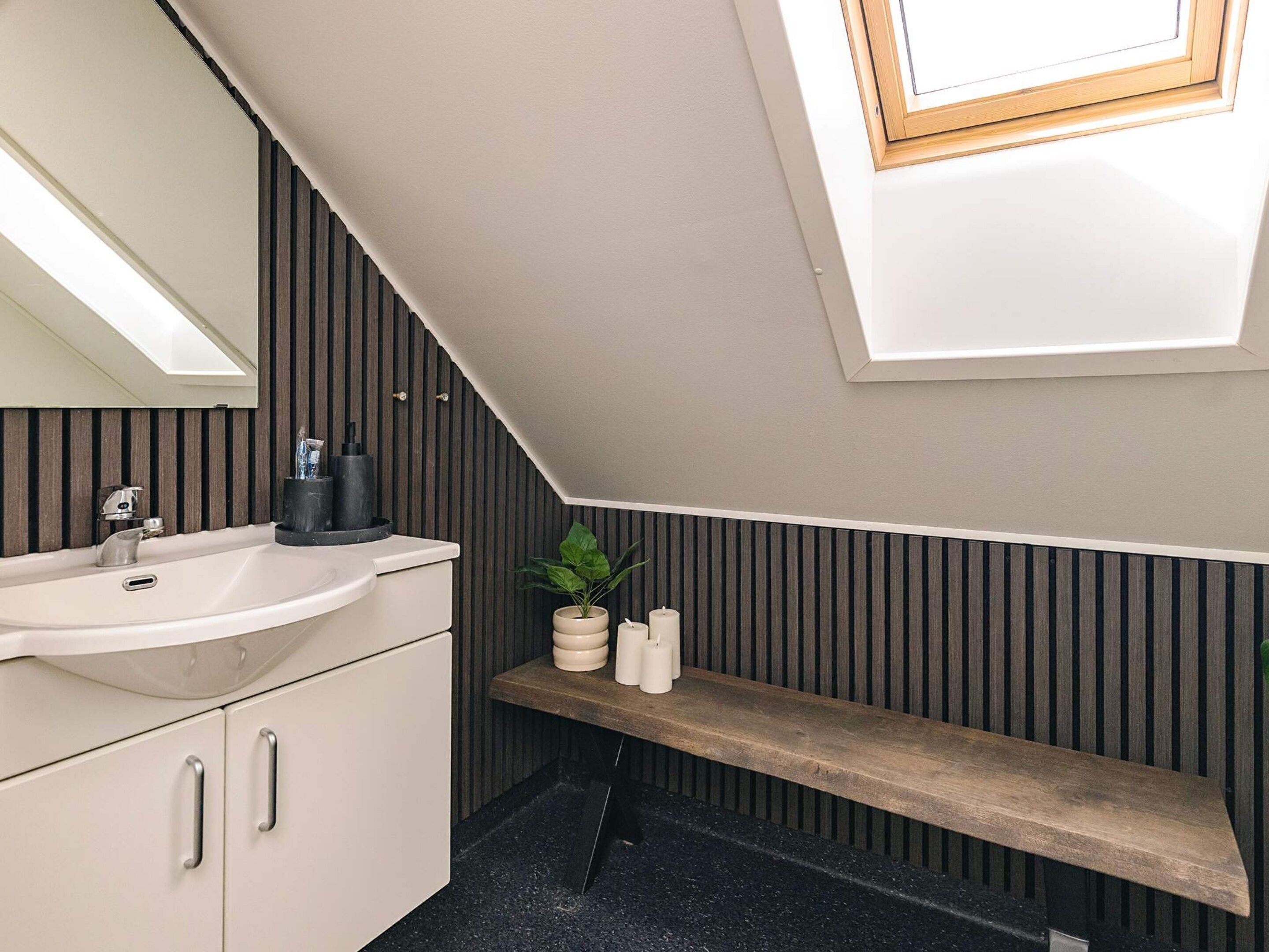 Ein modernes Badezimmer mit Dachfenster, einem Waschbecken und einem Holzboden.