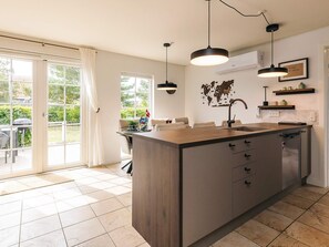 A modern kitchen with a central island, pendant lighting, and a view of the outdoors through large windows. - 5 Star Holiday Home in Brenderup Fyn (Middelfart)