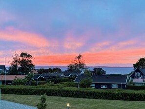 Een woonwijk met huizen, een grasveld en een zonsondergang boven het water.