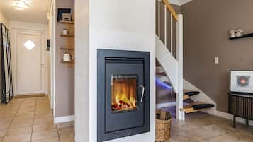 A modern interior with a fireplace, a staircase, and a wall-mounted shelf.