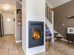 Um interior moderno com lareira, escada e prateleira na parede.