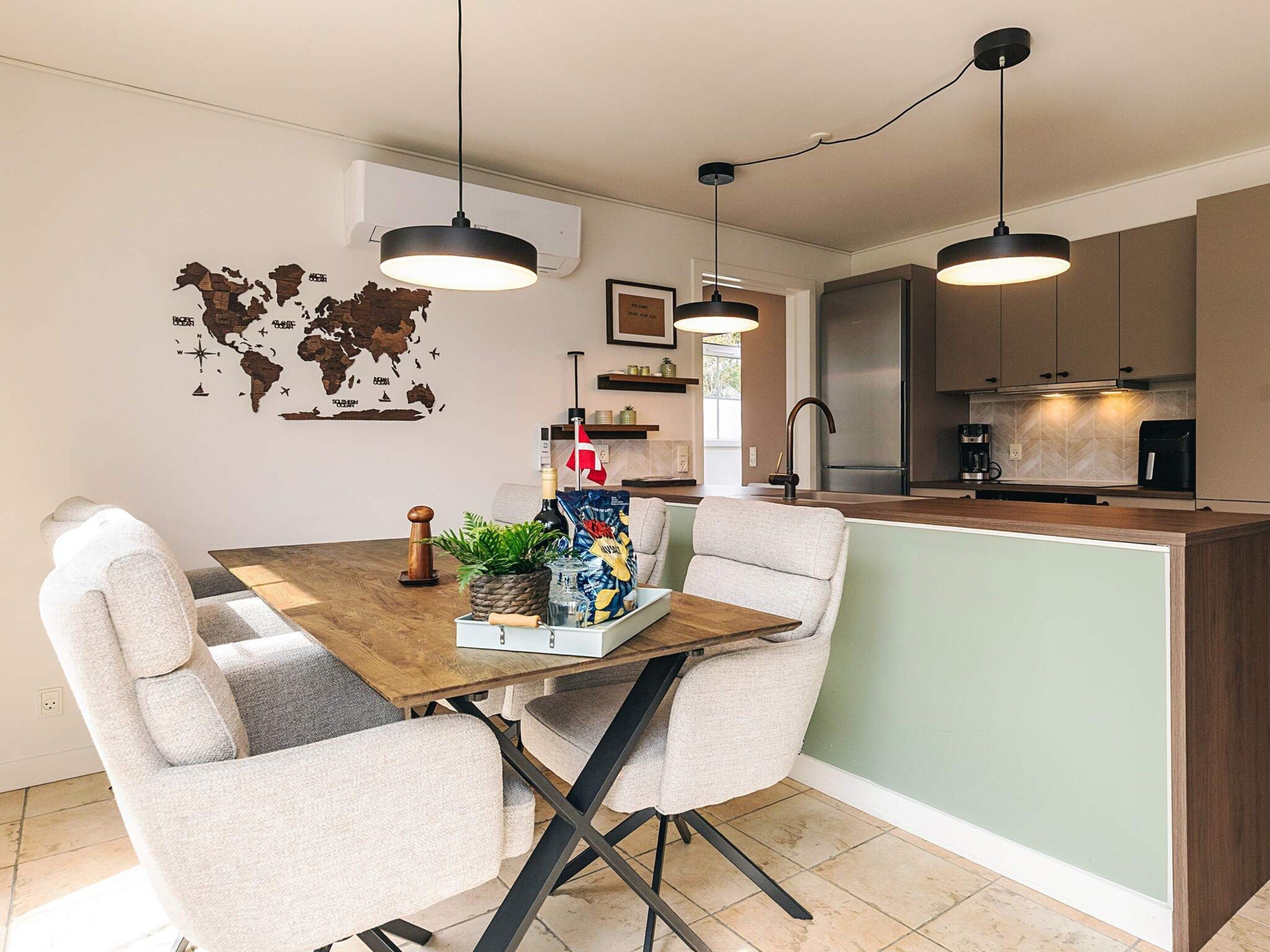 A modern kitchen with a central island, pendant lighting, and a world map wall decoration.
