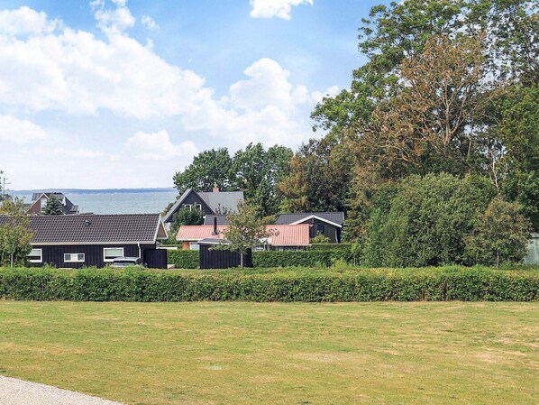 A residential area with houses, a grassy field, and a body of water in the background.