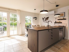 A modern kitchen with a central island, pendant lighting, and a world map wall decoration. - 5 Star Holiday Home in Brenderup Fyn (Middelfart)