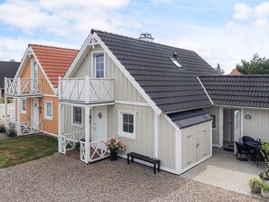 A two-story house with a balcony, a covered patio, and a gravel driveway. - 5 Star Holiday Home in Brenderup Fyn (Middelfart)