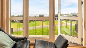 A room with a large sliding glass door leading to a balcony with a view of a green landscape and a body of water. - Well-maintained Holiday Home in Faborg (Faaborg)