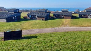 A row of modern cabins with flat roofs, set against a backdrop of a clear sky and a distant body of water. - Well-maintained Holiday Home in Faborg (Faaborg)