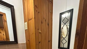 A bathroom with a wooden door, a white sink with soap dispenser, and a toilet with a decorative mirror above it. - Woodland Retreat next to the Mississippi River (Alma)