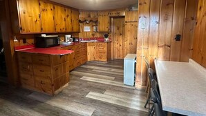 A compact kitchen with wooden cabinets, a microwave, a sink, and a refrigerator. - Woodland Retreat next to the Mississippi River (Alma)