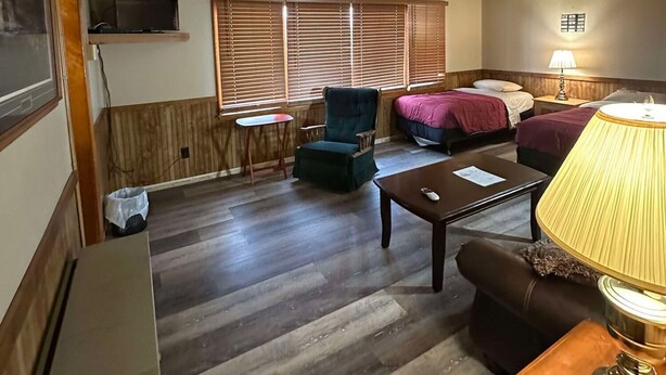 A room with a bed, a chair, a table, a lamp, and a TV mounted on the wall. - Woodland Retreat next to the Mississippi River (Alma)