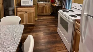 Una cocina compacta con armarios de madera, un microondas, una estufa y un refrigerador.