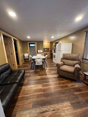 A spacious living area with a dining table, a sofa, and a recliner. - Woodlands Retreat next to the Mississippi River (Alma)