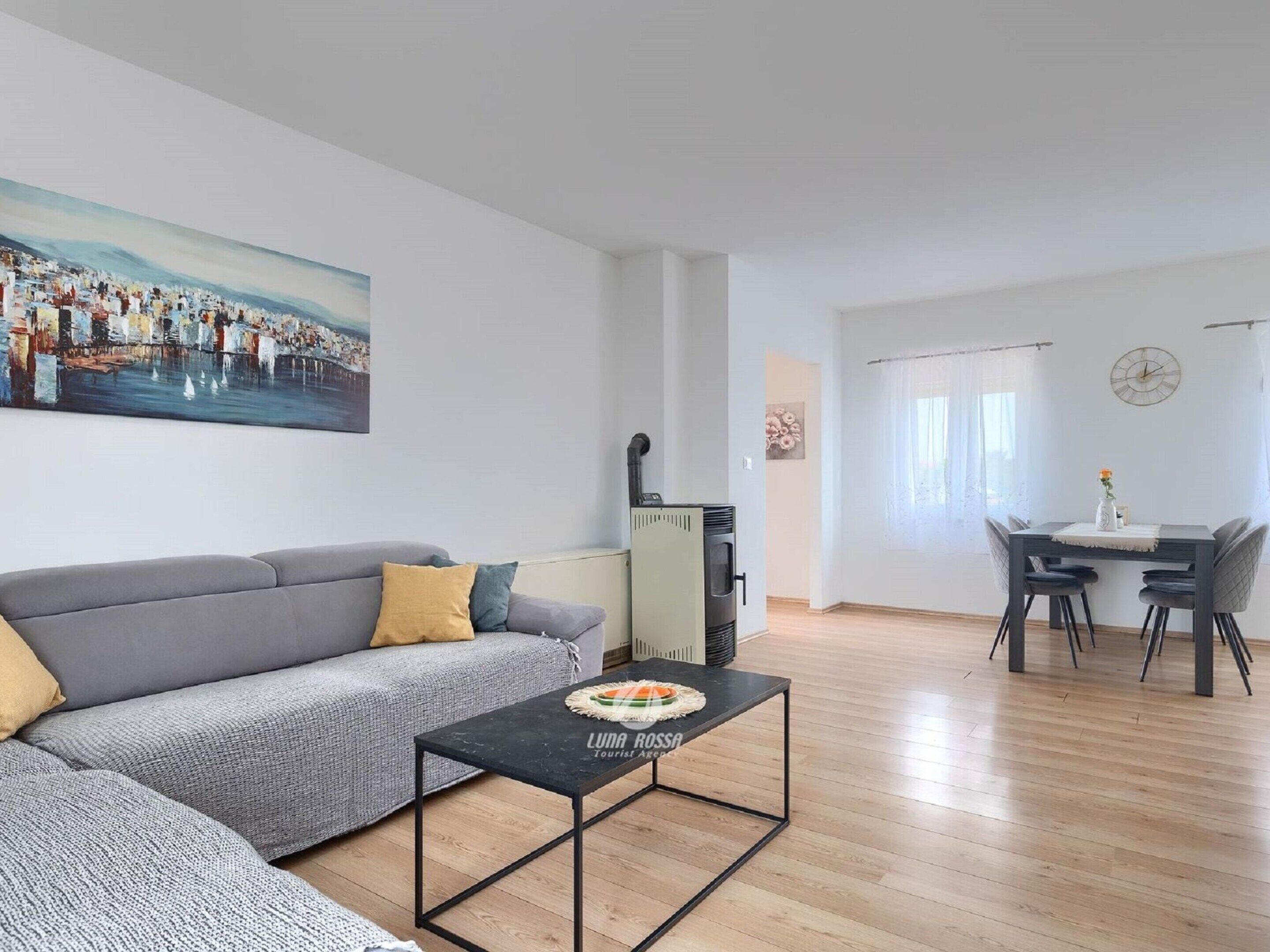 A modern living room with a grey sofa, a black coffee table, and a painting of a cityscape.
