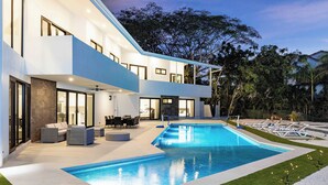 A modern house with a swimming pool, outdoor seating, and a well-maintained garden.