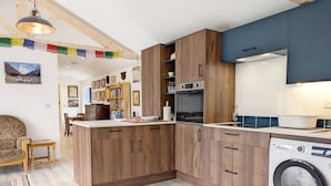 Eine moderne Küche mit Holzschränken, einem Einbauofen und einer Waschmaschine.