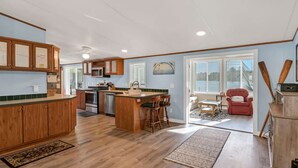 Una cocina amplia con armarios de madera, una isla central y un comedor con una silla roja.