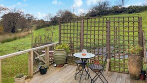 A wooden deck with a table and chairs, surrounded by potted plants and a wooden fence. - 1 bedroom accommodation in Tregaron (Tregaron)