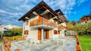 A two-story building with a balcony, outdoor seating, and a stone patio.