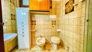 A bathroom with a bidet, toilet, sink, and a cabinet with multiple drawers.