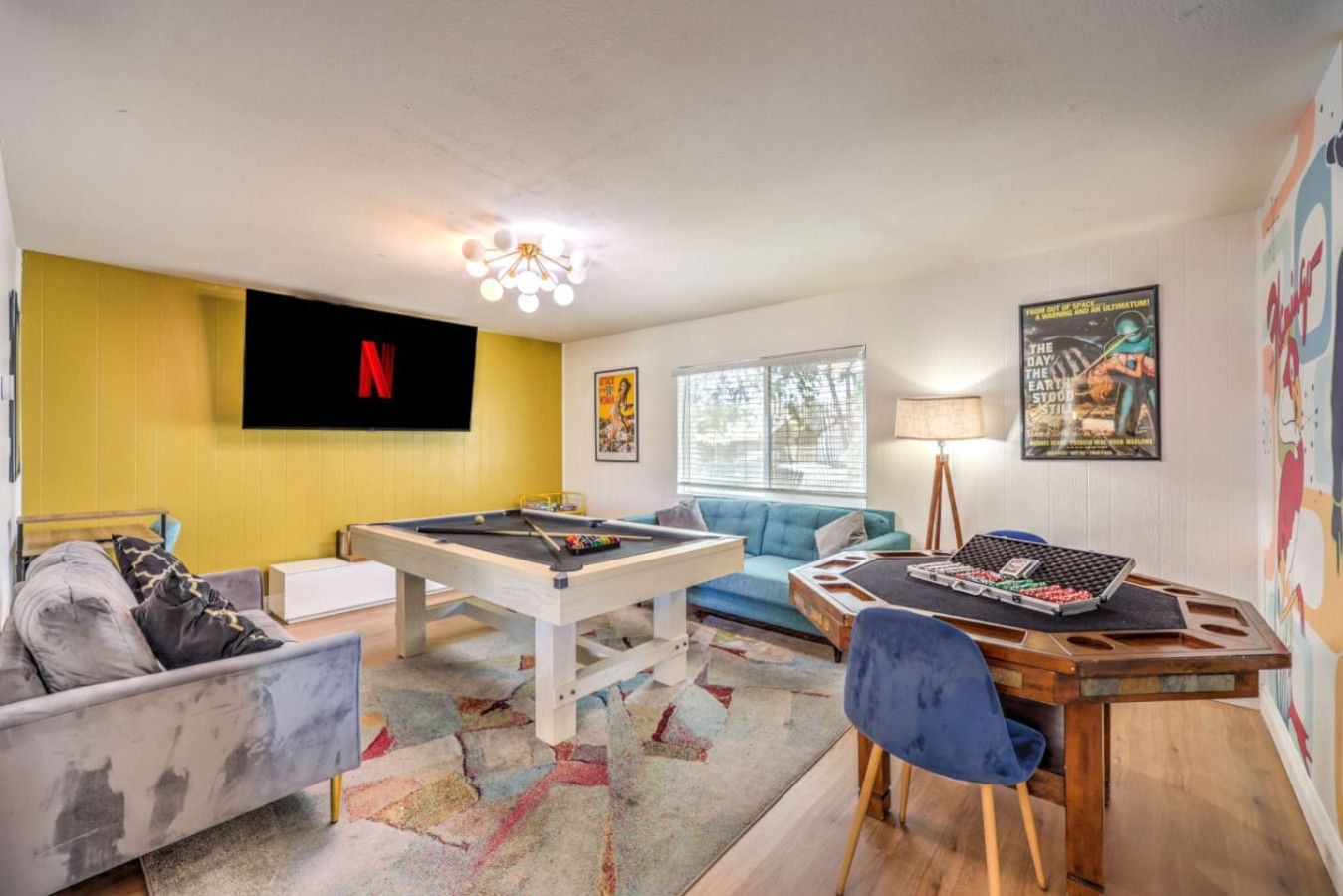 Ein Wohnzimmer mit Billardtisch, einer Couch, einem blauen Sofa und einem an der Wand befestigten Fernseher.