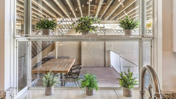 A modern outdoor seating area with a wooden table and chairs, surrounded by potted plants. - Oasis near STRIP-Lap Pool, Spa, Sauna, Poker, Deck (Las Vegas)