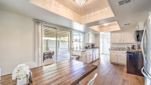 A modern kitchen with white cabinets, a wooden dining table, and a built-in oven. - Oasis near STRIP-Lap Pool, Spa, Sauna, Poker, Deck (Las Vegas)