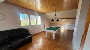 A room with a pool table, a black leather sofa, wooden flooring, and a wooden ceiling. - Villa Le domaine des Rêves (Plateau d'Hauteville)